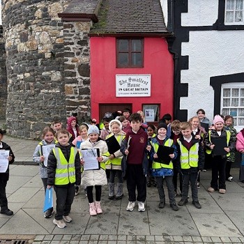 pupils year 3 to 6 standing out side the smallest house in Conwy