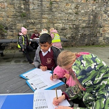 pupils writing on a sheet out side the castell walls