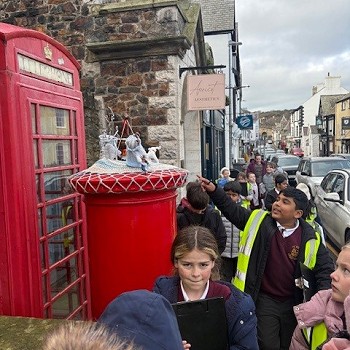 Pupils waling pas a red postbox this a crochets topper