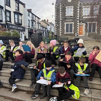 pupils sitting and holding clip boards and writing