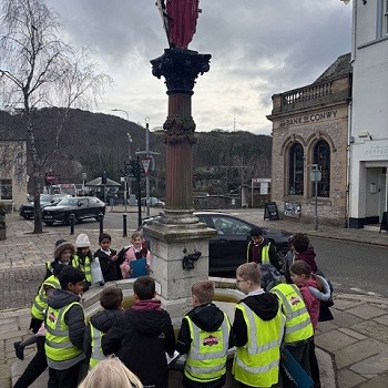 pupils standing by a monument in the Center of Conwy