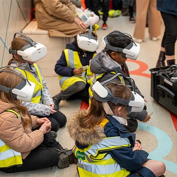 Plant yn gwisgo clustffonau VR ar y trên