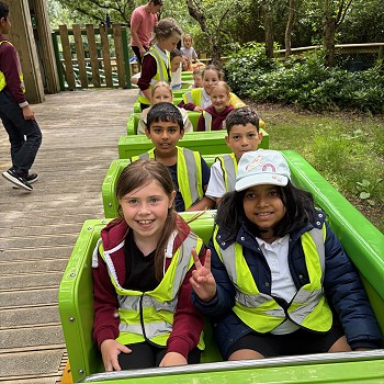 Grŵp o blant yn eistedd ar reid rholer-coaster.